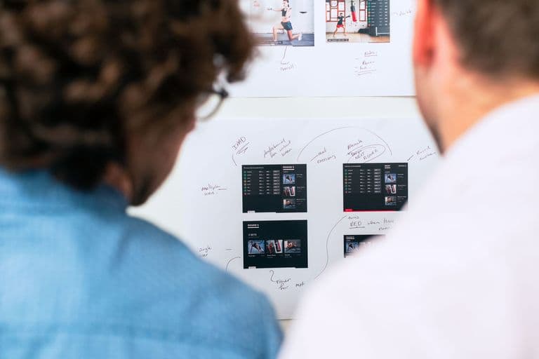 Two professionals planning software architecture at a whiteboard