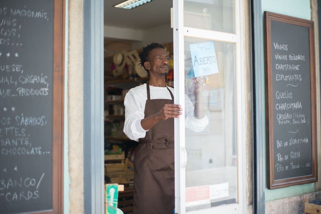 A shop owner opening the door of his storefront