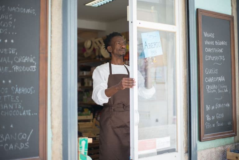 A shop owner opening the door of his storefront