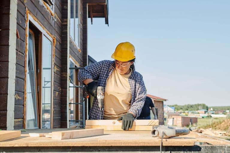 A carpenter drilling framing on a home renovation site