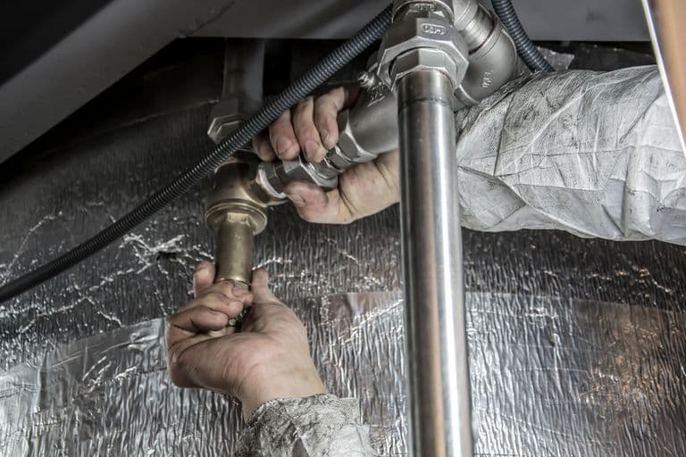 A plumber installing pipework under a sink