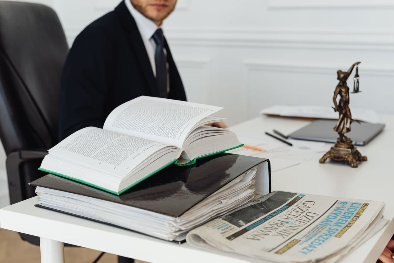 A law office desk with open legal books and a scales-of-justice figure