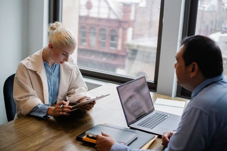 A consultant reviewing figures with a client at a workspace