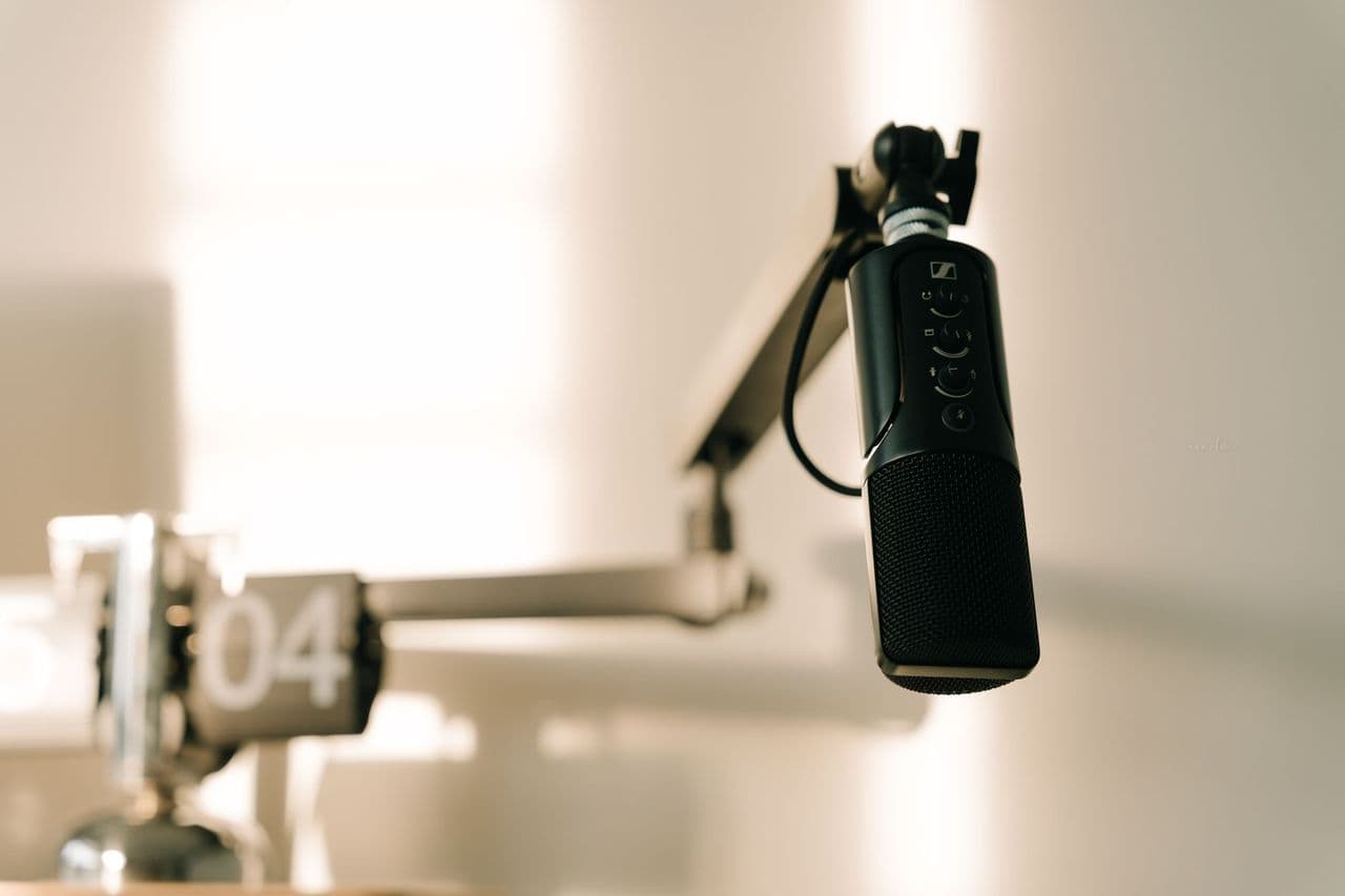 A sleek professional microphone on a boom arm in a minimalist studio