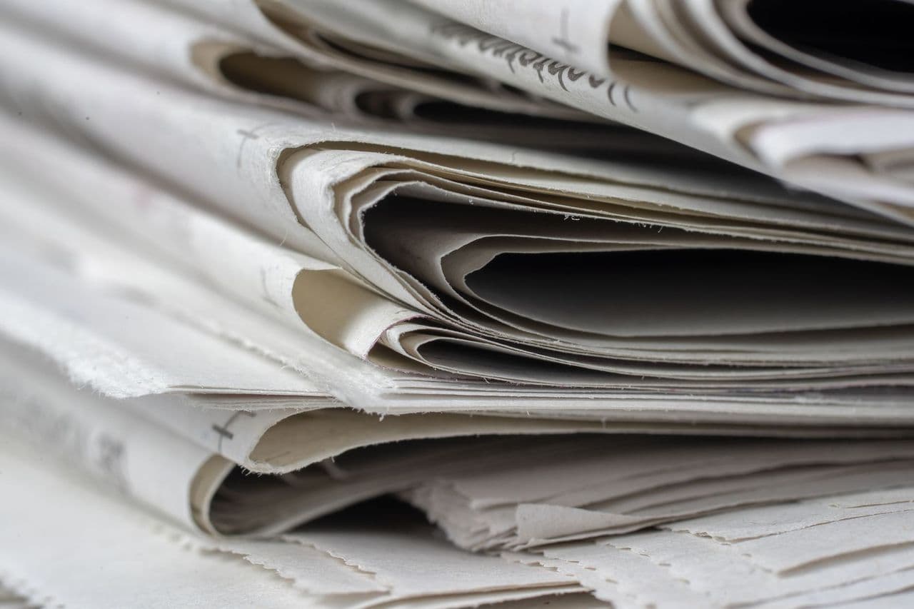 A detailed close-up view of stacked newspapers, highlighting textures and layers