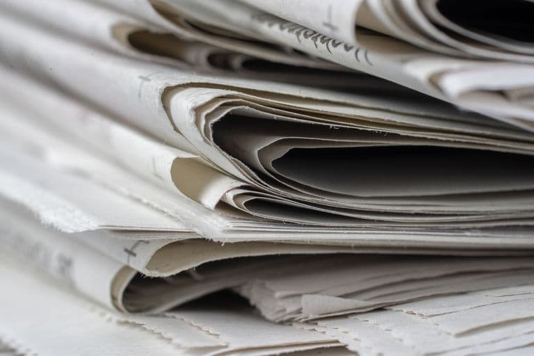 A detailed close-up view of stacked newspapers, highlighting textures and layers