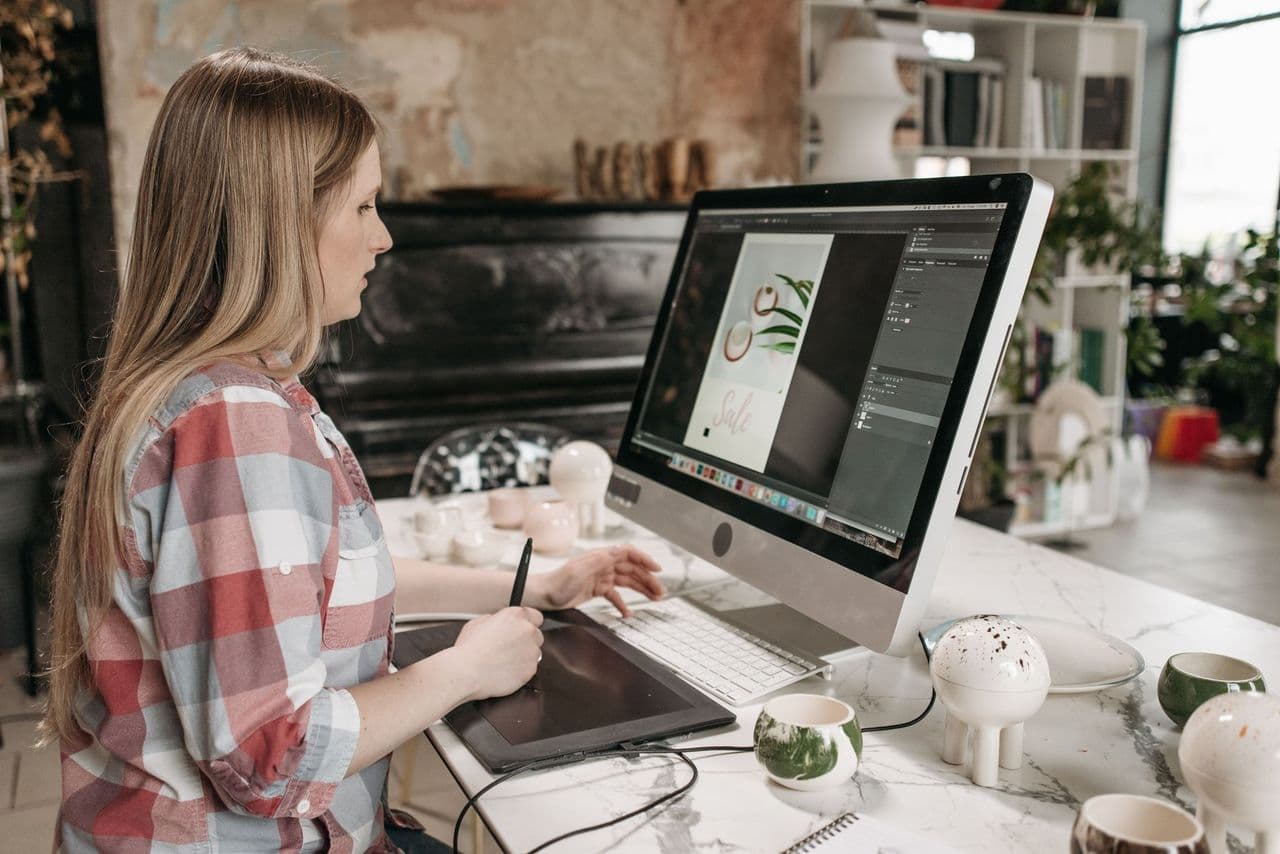 Woman using a digital drawing tablet in a stylish office workspace, focused on graphic design