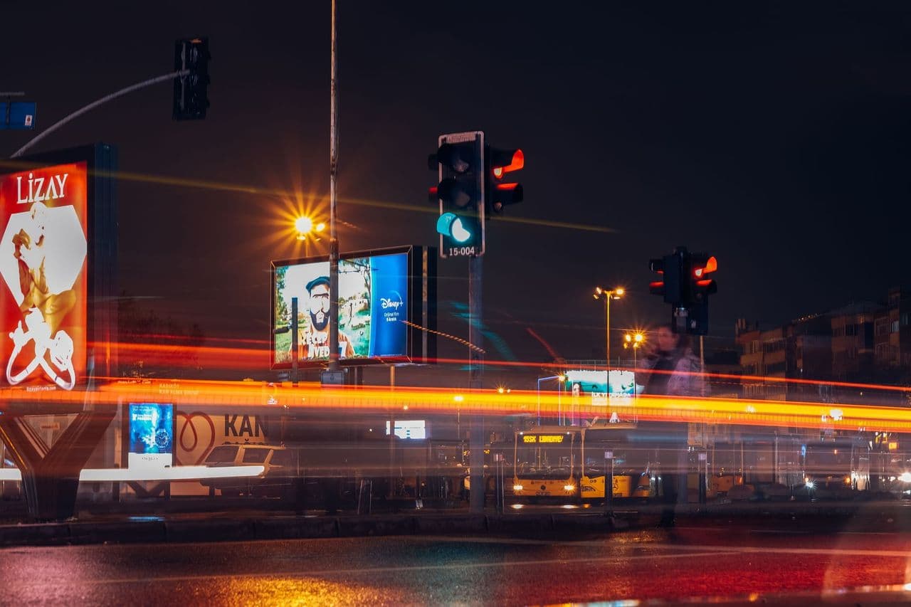 A vibrant city street scene captured at night with long exposure showing traffic lights and light trails