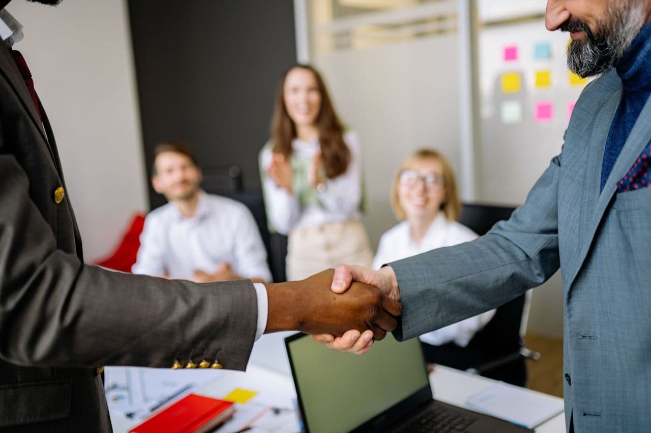Close-up of a handshake between colleagues in a professional office setting, emphasizing teamwork and agreemen