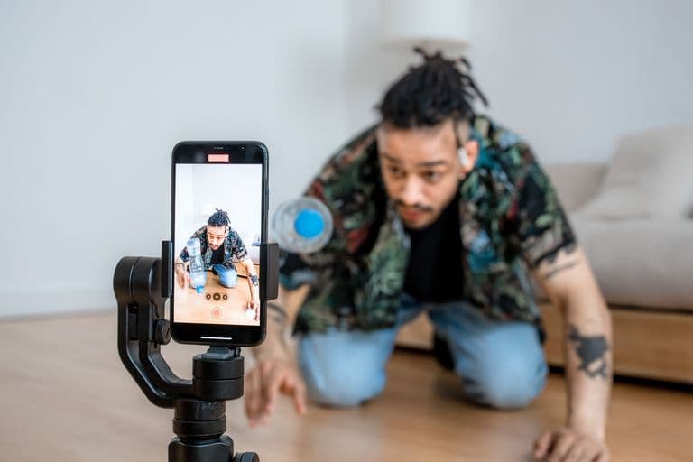 Man filming creative content with smartphone on gimbal indoors