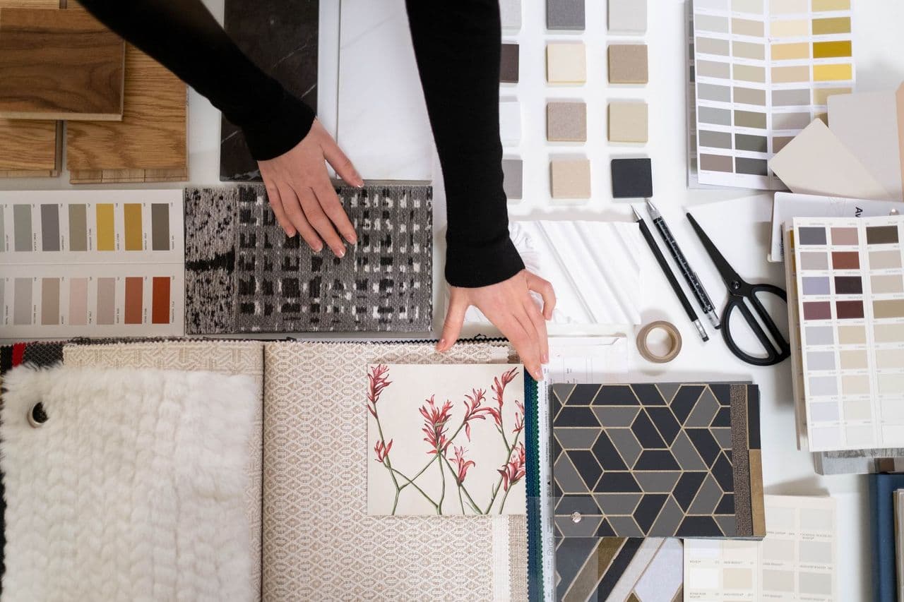 Hands arranging interior design samples and color swatches on a table