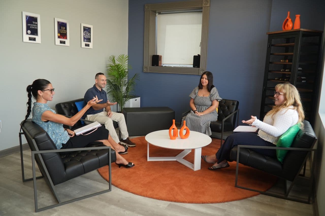 Four members of a Conduit pod in the office lounge, working through an account together around a low table