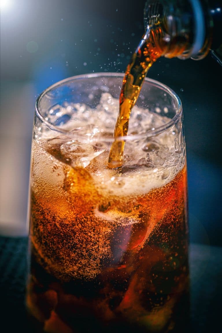 A cola poured over ice in a frosted glass