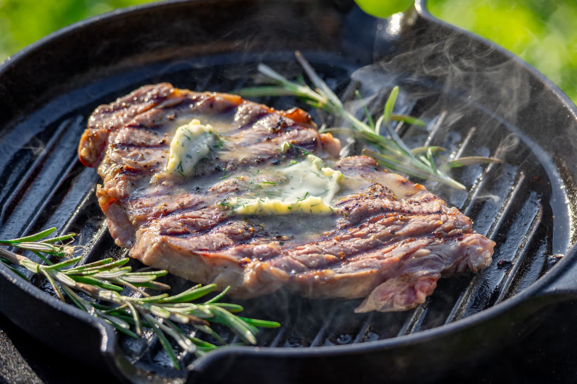 Steak cooking in a rustic cast iron pan